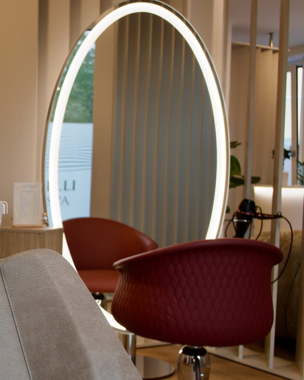 Friseursessel und beleuchteter ovaler Spiegel in der Kabine