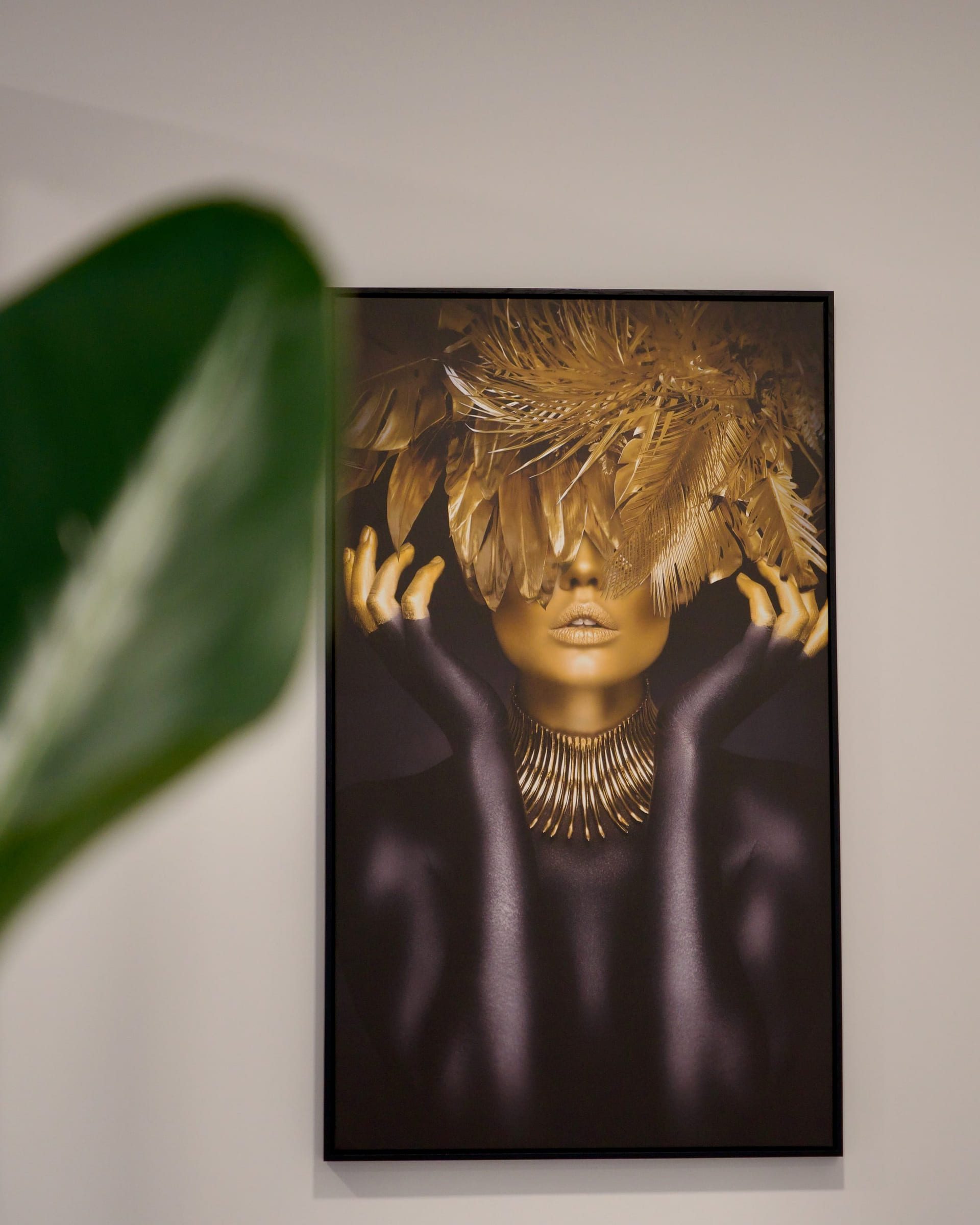 Goldenes Porträt an der Wand des Salons, davor eine Pflanze